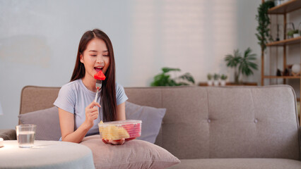 Young Asian woman embracing a longevity lifestyle by enjoying a nutritious fruit snack at home for...
