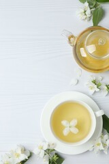 Green tea with jasmine in cup and teapot on white background, top view