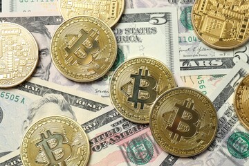 Close up of metal shiny bitcoin crypto currency coins on US dollar bills. Electronic decentralized money concept. 
