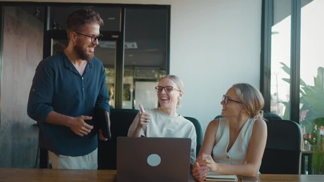 Happy business team exchanging high fives and celebrating successful completion of project in modern office workspace, radiating enthusiasm and collaboration. Successful team celebrates victory