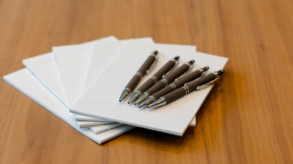 Notepad for agenda kept with pens on the desk in empty corporate conference room before business...