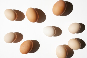 Gradient Colours and Dappled Eggs on White Surface, Overhead View. Organic Farm Eggs.	