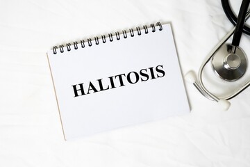 The medical concept "HALITOSIS" is written clearly on a white spiral notebook, accompanied by a stethoscope on a white background.