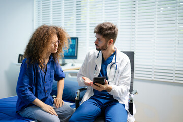 Obraz premium Doctor consults patient in modern clinic using a digital tablet to discuss diagnosis and treatment. Concept of trust, care