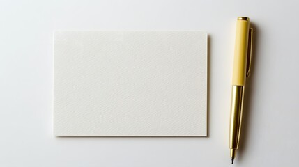 Photograph of a beige rectangle next to a gold pen on a white surface.