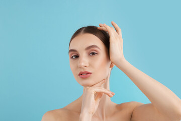 Naklejka premium Portrait of charming young woman on light blue background