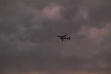 Passenger jet aircraft silhouetted against dramatic and moody storm clouds