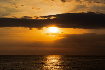 Golden sunset light reflects beautifully on dark ocean waves under dramatic clouds