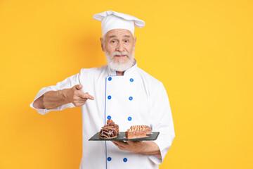 Professional pastry chef with delicious desserts on orange background