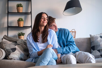 Young couple sitting on the sofa making peace after an argument. Reconnecting emotionally, sharing...