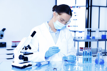 Scientist working with sample in Petri dish at table in laboratory