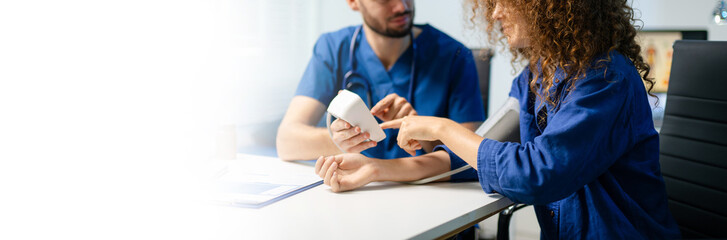 Female patient gets blood pressure checked by doctor with digital monitor. Health checkup, patient care, and medical technology