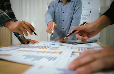 A professional business team collaborates around a conference table, analyzing charts, discussing...
