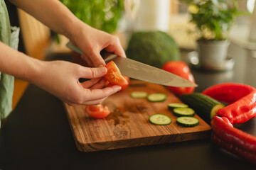 Woman cutting fresh vegetables in the kitchen. Healthy cooking, food preparation and lifestyle concept
