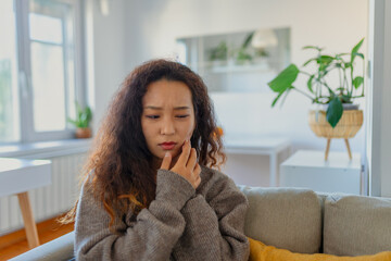 Portrait of unhappy young Asian woman suffering from toothache at home. Healthcare, dental health...