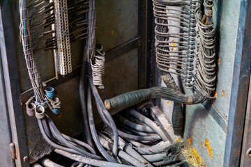 Rusty, open electrical cabinet with tangled wires and old terminal strips in an abandoned...