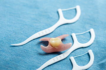 Partial denture and dental floss on pastel blue. Dental appliance for tooth replacement