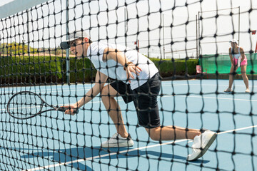 Man on serve with tenis racket and dressed in white t-shirt, black shorts and white shoes.