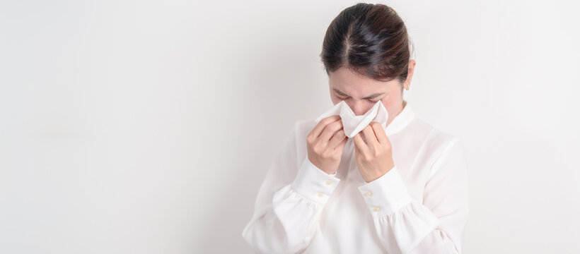business woman blowing her nose with tissue for concepts of Common Cold, Influenza, Flu, Hay, Fever, Covid 19, Respiratory Infection, Sinusitis, Allergic Rhinitis, Allergy, Medical and health care - Powered by Adobe