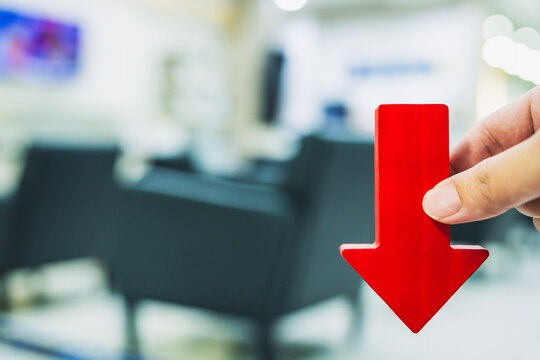 A red arrow pointing down over empty corporate chairs signifies a company's downturn amid a global economic recession.