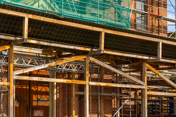 historic brick church under renovation, covered with scaffolding and green protective mesh....
