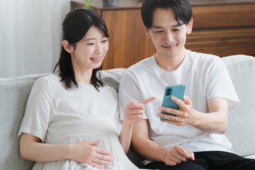 スマートフォンを操作する妊婦と夫 ライフスタイルイメージ
