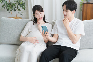 スマートフォンを操作する妊婦と夫　ライフスタイルイメージ