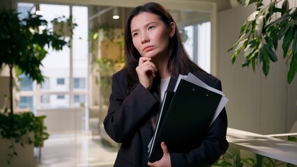 Thoughtful Asian doubtful woman pensive thinking puzzled businesswoman with documents girl female...