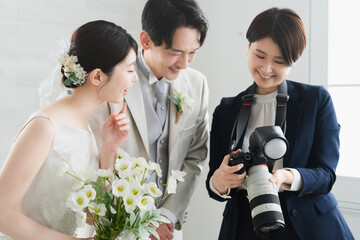 カメラマンが撮影した写真を確認する新婦と新郎　ウエディングイメージ
