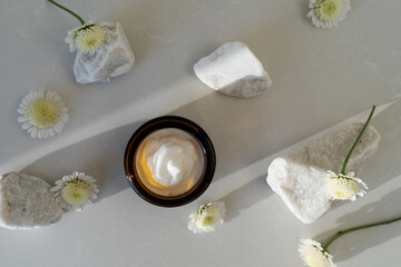 Cosmetic cream in container for face and body skin care top view. Natural organic product in glass jar for wellness, beauty and spa.