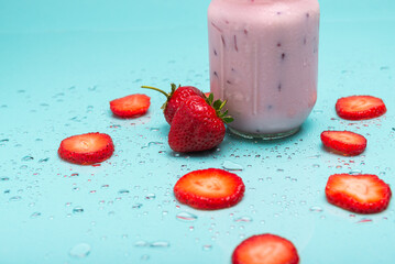 A mason jar brimming with a cool strawberry drink, garnished with fresh strawberries and metal straw