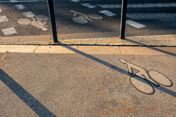 Bike symbol on asphalt with harsh shadow lines and barrier contrast, capturing mobility and movement in public infrastructure