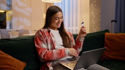 Caucasian woman on sofa evening home enter code credit card laptop banking payment internet store...