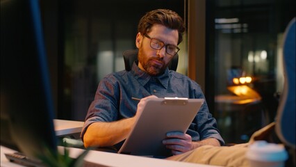 Caucasian business man trader businessman analyst writing document in night office paperwork...