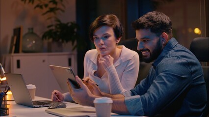 Multiracial teamwork Indian man Caucasian woman business partners co-workers colleagues talking at dark night evening office girl guy businessman businesswoman designers discuss project startup laptop