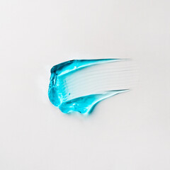 A smear of blue cosmetic hair gel on a white background