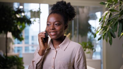 Smiling business woman African American ethnic girl businesswoman talking mobile phone in office female employer student manager call smartphone answer speaking cellphone conversation job chatting