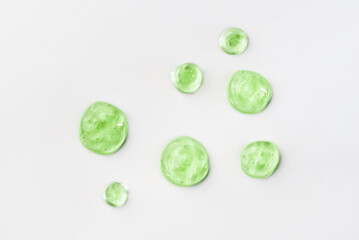 Green cosmetic gel drops on a white background