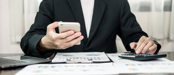 Asian businessman sit at their desks and calculate financial graphs showing results about their...