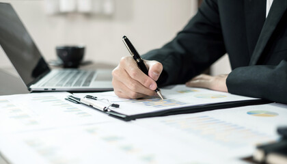 Asian businessman sit at their desks and calculate financial graphs showing results about their...