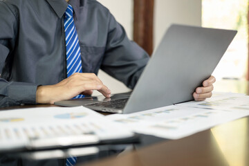 Asian businessman sit at their desks and calculate financial graphs showing results about their...