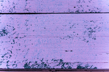 Close-up of weathered pink painted wooden planks showing chipped texture and subtle grain detail....