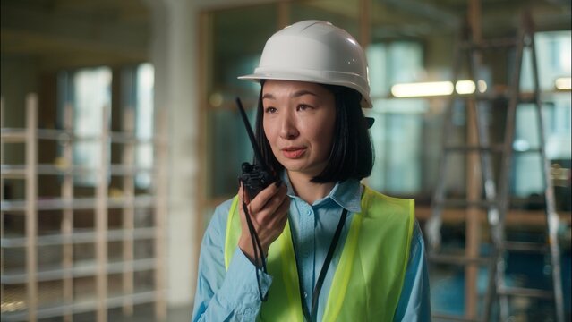 Builder engineer Asian woman building industry worker Chinese girl in hard hat inspector answer walkie talkie radio remote control female Japanese Korean architect foreman developer in factory work
