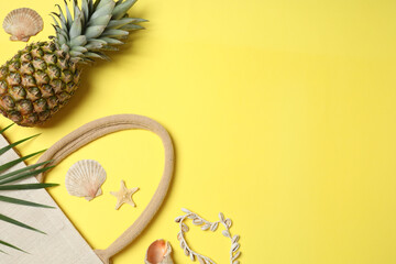 Tropical vibes shot from above. Straw hat, sunglasses, pineapple, wicker bag, beach accessories on...