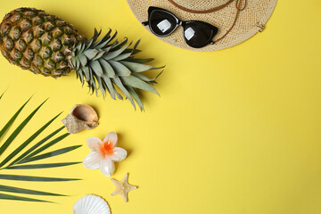 Tropical vibes shot from above. Straw hat, sunglasses, pineapple, wicker bag, beach accessories on...