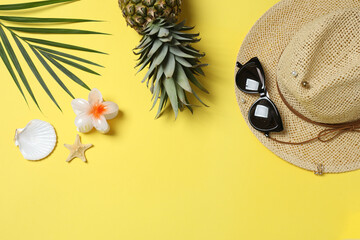 Tropical vibes shot from above. Straw hat, sunglasses, pineapple, wicker bag, beach accessories on...