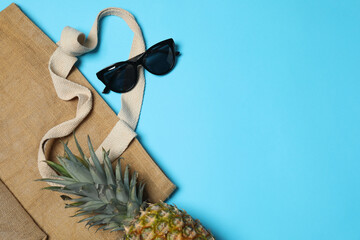 Tropical vibes shot from above. Straw hat, sunglasses, pineapple, wicker bag, beach accessories on...