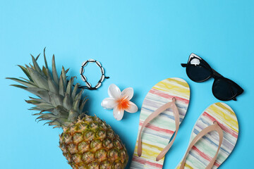 Tropical vibes shot from above. Straw hat, sunglasses, pineapple, wicker bag, beach accessories on...