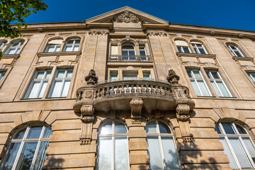 A magnificent old building with a detailed facade, high windows, and a circular balcony in the center. The Baroque elements and the blue sky emphasize the classical style.