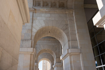 Light filters through stone arches in a neoclassical government building. The symmetry of the corridor and decorative details of the ceiling distinguish architectural elegance.